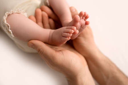 Childrens feet in hold hands of mother on white. Mother and newborn Child. Happy Family people concept.の写真素材