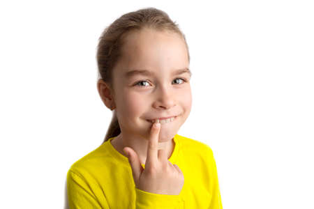Little girl stands on a white background with a beautiful smile, children crooked teeth, pediatric dentistry. Crooked teeth close-up. Correction of malocclusion is required.の写真素材