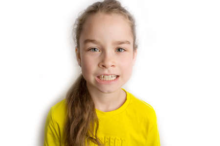 Little girl stands on a white background with a beautiful smile, children crooked teeth, pediatric dentistry. Crooked teeth close-up. Correction of malocclusion is required.の写真素材