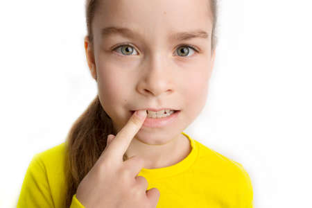 Little girl stands on a white background with a beautiful smile, children crooked teeth, pediatric...