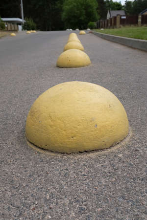 Yellow concrete hemispheres on the parking lot near the retail supermarket so that cars do not park in this place. Artificial obstacle for driving and parking. Anti-parking barrier.の写真素材