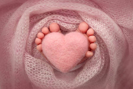 Feet of a newborn with a wooden heart, wrapped in a soft blanket. pink heartの写真素材