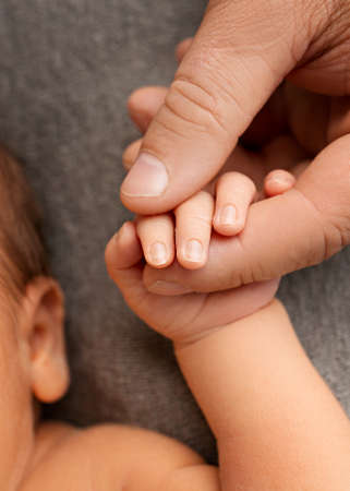 A newborn child holds with his hand, fingers the hand, the fingers of a parent, father or mother.の写真素材