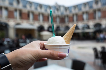 A beautiful female hand holds a cardboard glass with ice cream. Cocktail, juice, lemonade. But the...