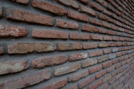 Red background of old vintage brick wall texture. Close up view of old stone brick wall with...