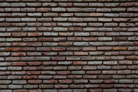 Red background of old vintage brick wall texture. Close up view of old stone brick wall with...