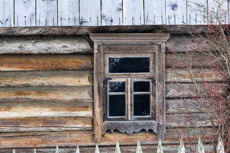 Rustic wooden house made of round logs. Abandoned villages and houses. Ancient window design. Wooden window frame. Snow covered village. Age-old buildings. Professional photography.の写真素材