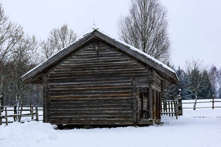 Winter Russian landscape. An old wooden hut, a log house with a thatched roof. Abandoned Russian...