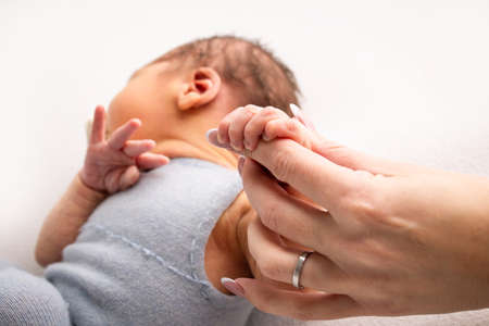 Close-up little hand of child and palm of mother and father. The newborn baby has a firm grip on the...