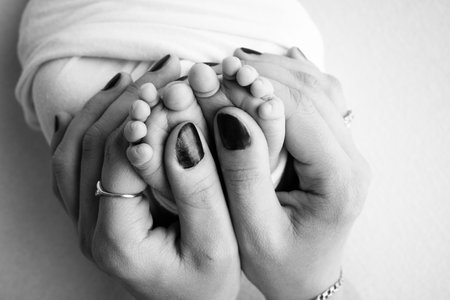 Mother is doing massage on her baby foot. Closeup baby feet in mother hands. Prevention of flat feet, development, muscle tone, dysplasia. Family, love, care, and health concepts. Black and white.の写真素材