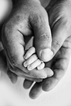 A newborn holds on to moms, dads finger. Hands of parents and baby close up. A child trusts and...