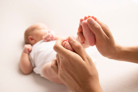 Mother is doing massage on her baby foot. Close up baby feet in mother hands on a white background. Prevention of flat feet, development, muscle tone, dysplasia. Family, love, care, and health conceptの写真素材