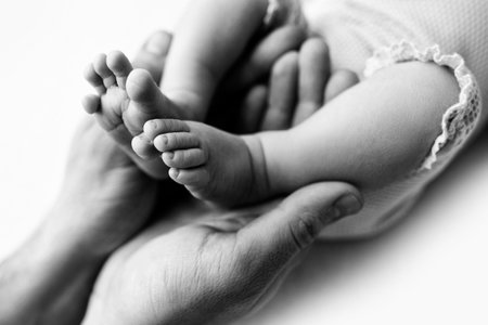 Feet of a newborn in the hands of a father, parent. Black and white.の写真素材