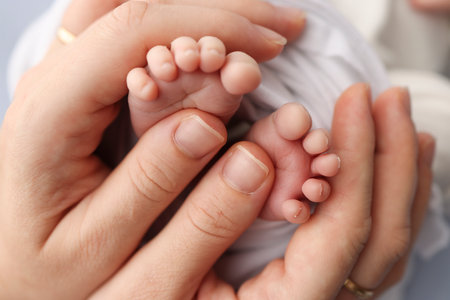 Small feet of a newborn in the hands of parents. Loving palms of the hands of mother. Conceptual image of fatherhood. Close-up, selective focus. Professional photography a white background.の写真素材