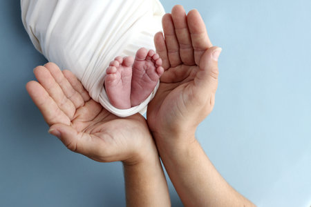 Tiny foot of a newborn baby. Soft legs of a newborn in a white blanket. Close up the toes, heels and feet of a newborn baby. Studio macro photography baby feet on a white background.の写真素材