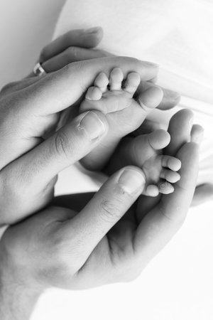 The palms of the father, the mother are holding the foot of the newborn baby on white background....