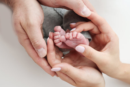 The palms of the father, the mother are holding the foot of the newborn baby on white background. Feet of the newborn on the palms of the parents. Photography of a childs toes, heels and feet.の写真素材