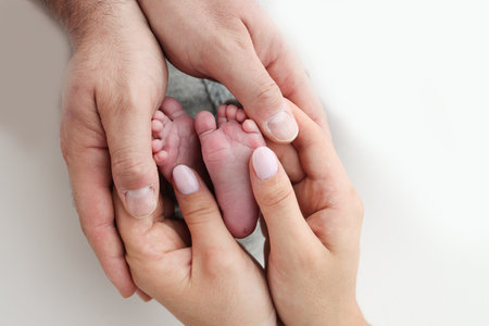 The palms of the father, the mother are holding the foot of the newborn baby on white background. Feet of the newborn on the palms of the parents. Photography of a childs toes, heels and feet.の写真素材