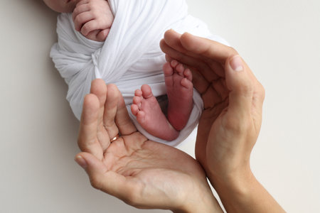 The palms of the father, the mother are holding the foot of the newborn baby.の写真素材