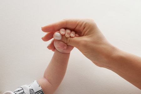 Parents hands hold the fingers of a newborn baby. A fist of a newborn babyの写真素材
