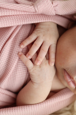 Tiny hand of a newborn baby. Soft hands of new born in pink clothes. Fingers of a newborn baby hands close up. Studio macro photography . Happiness of a woman. Concept.の写真素材