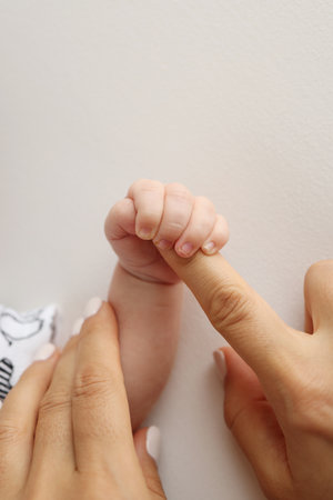 Parents hands hold the fingers of a newborn baby. The hand of mother and father