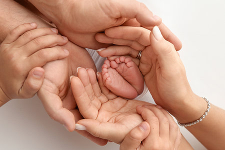 Childrens foot in the hands of mother, father, parents. Feet of a tiny newbornの写真素材