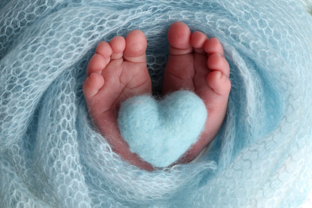 The tiny foot of a newborn baby. Soft feet of a new born in a blue wool blanket.の写真素材