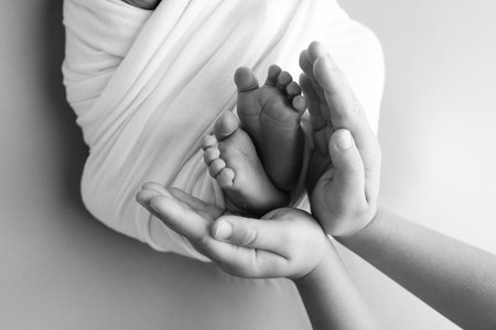 The palms of the father, the mother are holding the foot of the newborn baby.