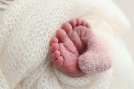 The tiny foot of a newborn baby. Soft feet of a new born in a white wool blanketの写真素材