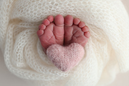 The tiny foot of a newborn baby. Soft feet of a new born in a white wool blanket. Close up of toes,...