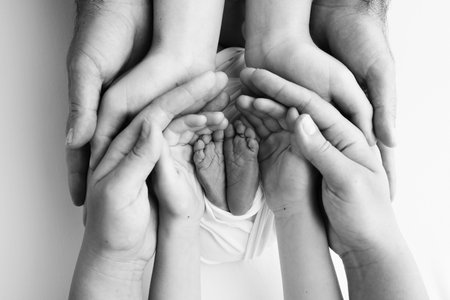 The palms of the father, the mother are holding the foot of the newborn baby.の写真素材