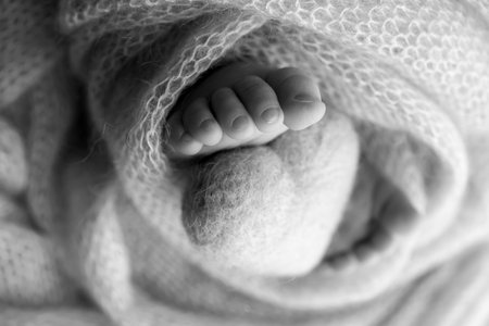 The tiny foot of a newborn baby. Soft feet of a new born in a wool blanket. Close up of toes, heels...