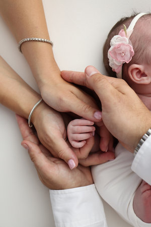 Small hand of a newborn baby with tiny fingers, head, nose and ear of a newborn. Palm hand of parents, father and mother of a newborn. Studio macro photography.の写真素材