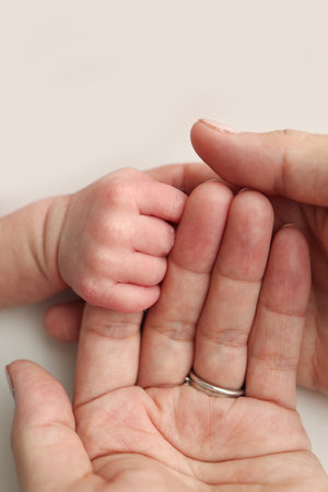 The newborn baby has a firm grip on the parents finger after birth. Close-up little hand of child and palm of mother and father. Parenting, childcare and healthcare concept.の写真素材