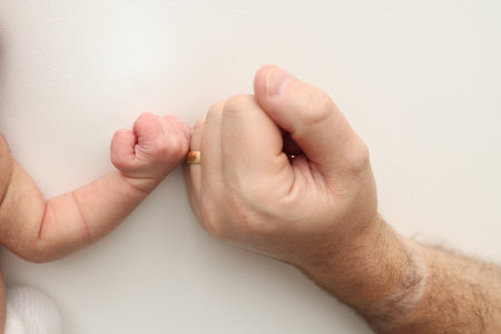 Dad and newborn baby boy son keep their hands in a fist, small and big fists. Father and son.の写真素材