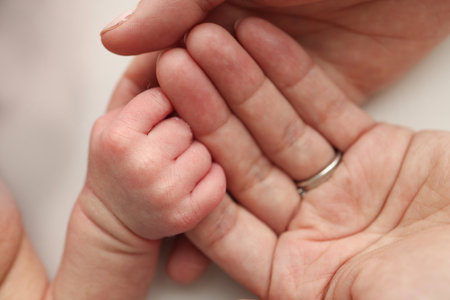 The newborn baby has a firm grip on the parents finger after birth. Close-up little hand of child and palm of mother and father. Parenting, childcare and healthcare concept.の写真素材