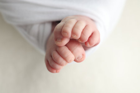 The tiny foot of a newborn. Soft feet of a newborn in a white blanket. Close up of toes, heels and feet of a newborn baby. Studio Macro photography. Womans happiness.の写真素材