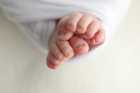 The tiny foot of a newborn. Soft feet of a newborn in a white blanket. Close up of toes, heels and feet of a newborn baby. Studio Macro photography. Womans happiness.の写真素材