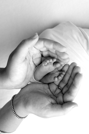 The palms of the parents. A father and mother hold the feet of a newborn child in a blanket.の写真素材