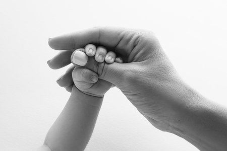 Parents hands hold the fingers of a newborn baby. Tiny fingers in a black whiteの写真素材
