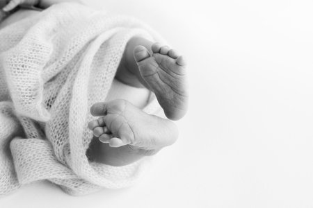 The tiny foot of a newborn baby. Soft feet of a new born in a wool blanket.の写真素材