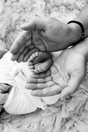 The palms of the father and mother are holding the foot of the newborn babyの写真素材