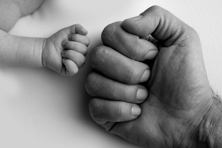 Two hands: man and child. Father and son touching fists. Dad and newborn son boys holding hands...