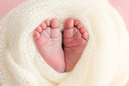 Close up of toes, heels and feet of a newborn baby.The tiny foot of a newborn. Soft feet of a newborn in a white blanket, pink background.の写真素材