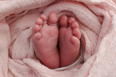 Baby foot on pink soft coverlet, blanket.Close-up of tiny, cute, bare toes, heels and feet of a newborn girl, boy.Detail of a newborn baby legs. Macro horizontal professional studio photo.の写真素材