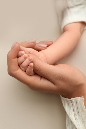 Close-up little hand of child and palm of mother and father. The newborn baby has a firm grip on the parents finger after birth. A newborn holds on to moms, dads finger.の写真素材