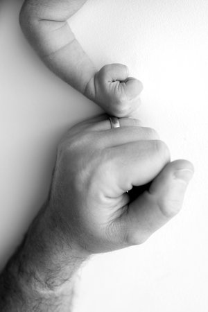 Two hands: man and child. Father and son touching fists. Dad and newborn son boys holding hands together. Little and big fists of father and son. Black and white professional photo.の写真素材