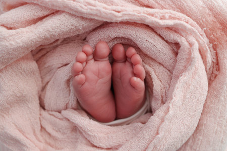 Baby foot on pink soft coverlet, blanket.Close-up of tiny, cute, bare toes, heels and feet of a newborn girl, boy.Detail of a newborn baby legs. Macro horizontal professional studio photo.の写真素材