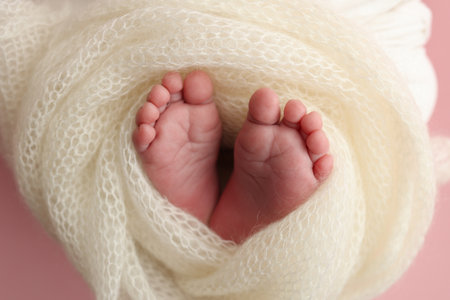 Close up of toes, heels and feet of a newborn baby.The tiny foot of a newborn. Soft feet of a newborn in a white blanket, pink background.の写真素材